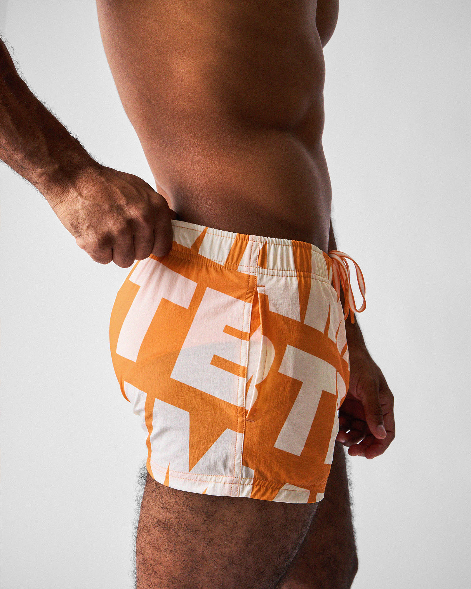 Teamm8 Headliner Swim Short Orange - deconstructed logo print detail, close-up
